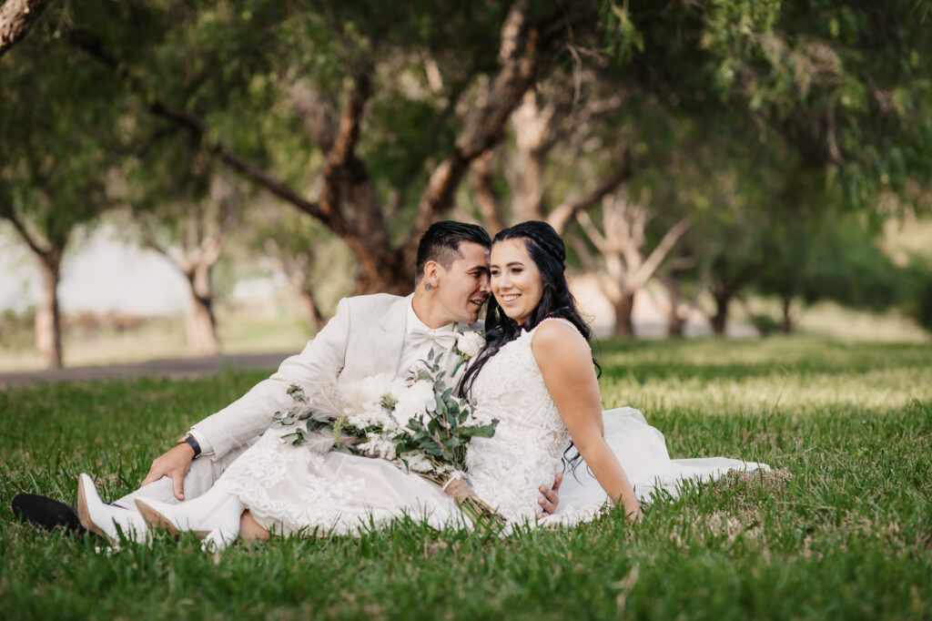 husband and wife sitting down on the grass laughing