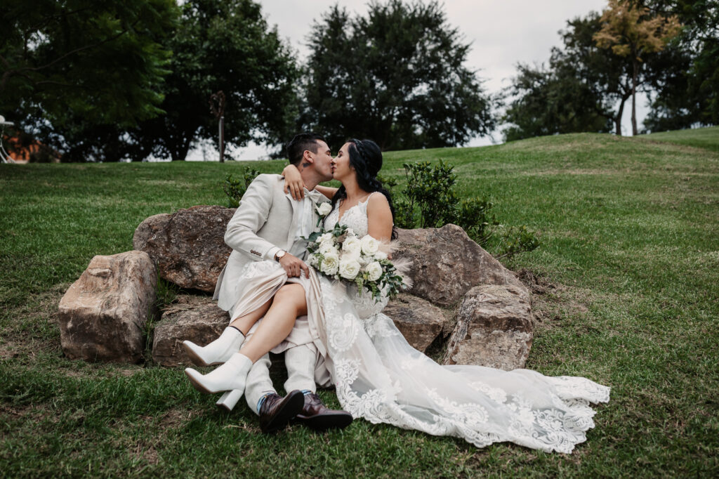 husband and wife kissing sat on a rock in the hunter valley