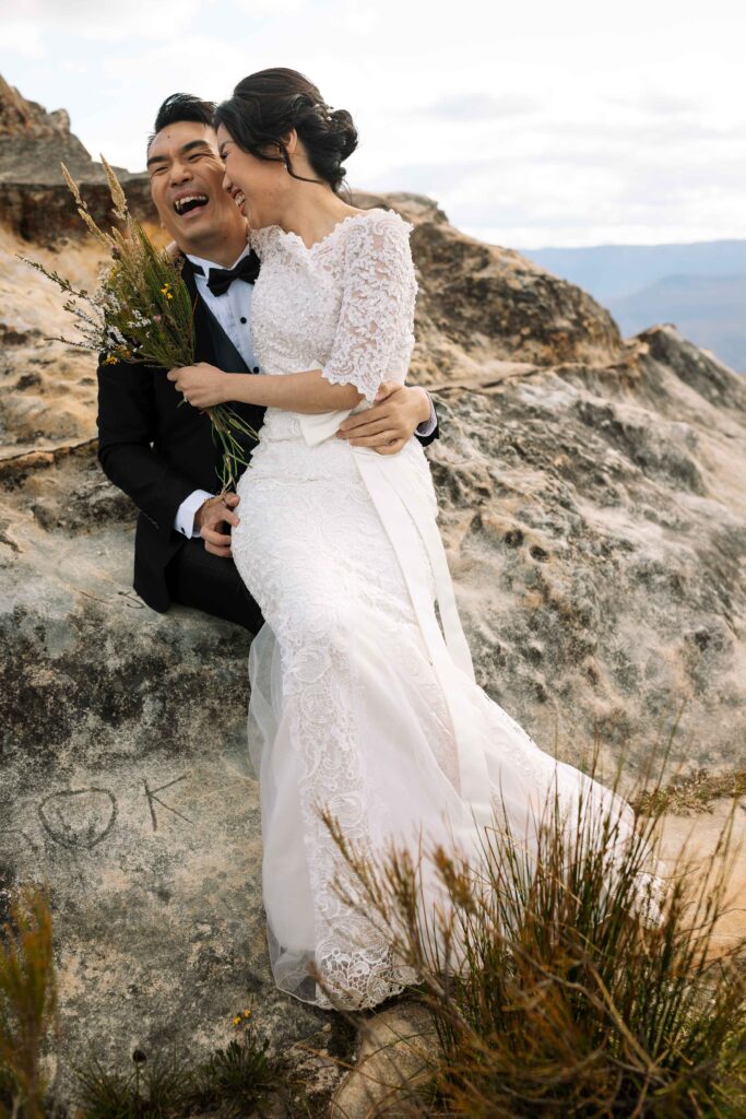 Engaged couple sat on a rock having an engagement session at the top of the blue mountains