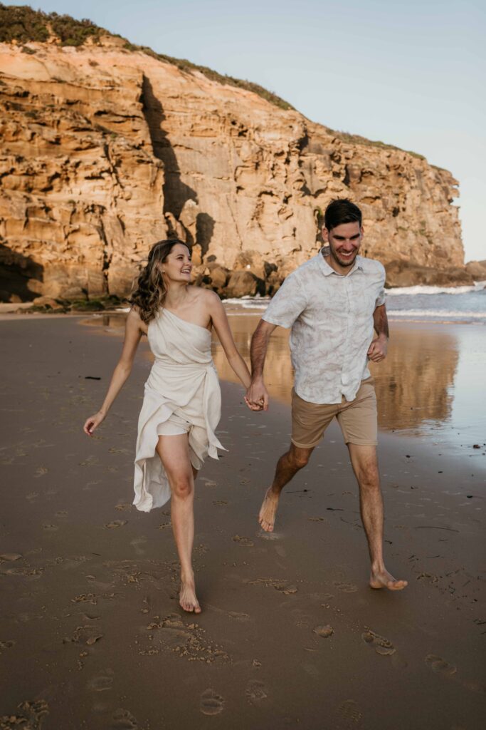 Couple running. Sunset Engagement Session on Redhead beach, NSW