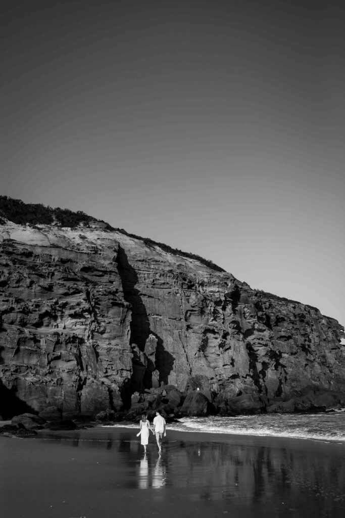 Couple walking together on redhead beach in Black and White