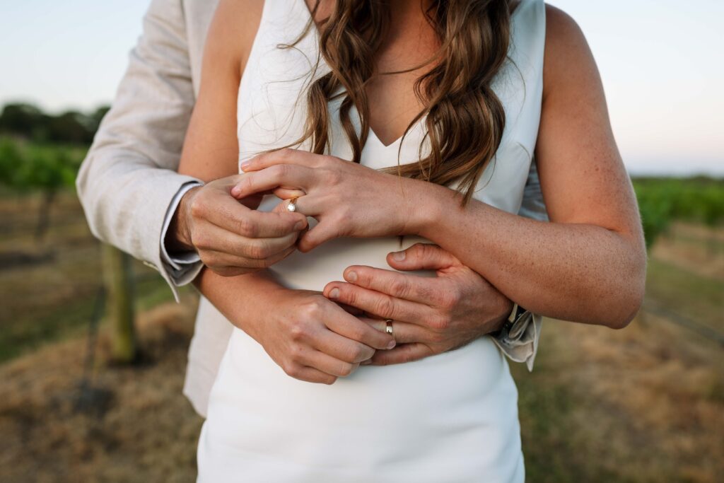 husband and wife placing wedding rings on each others hand in the Hunter valley, NSW