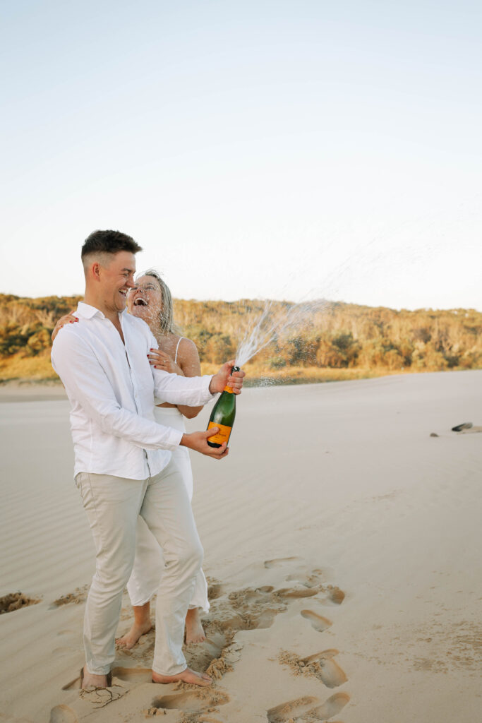 Engagement session sunset at Stockton sand dunes. Champaign popping and spraying