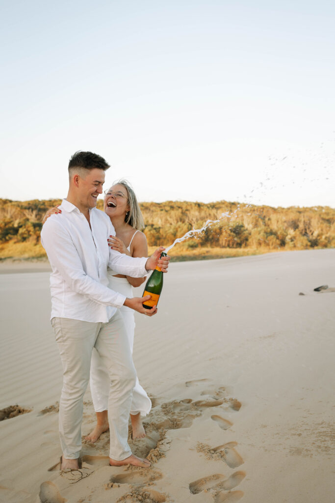 Engagement session sunset at Stockton sand dunes. Champaign popping and spraying