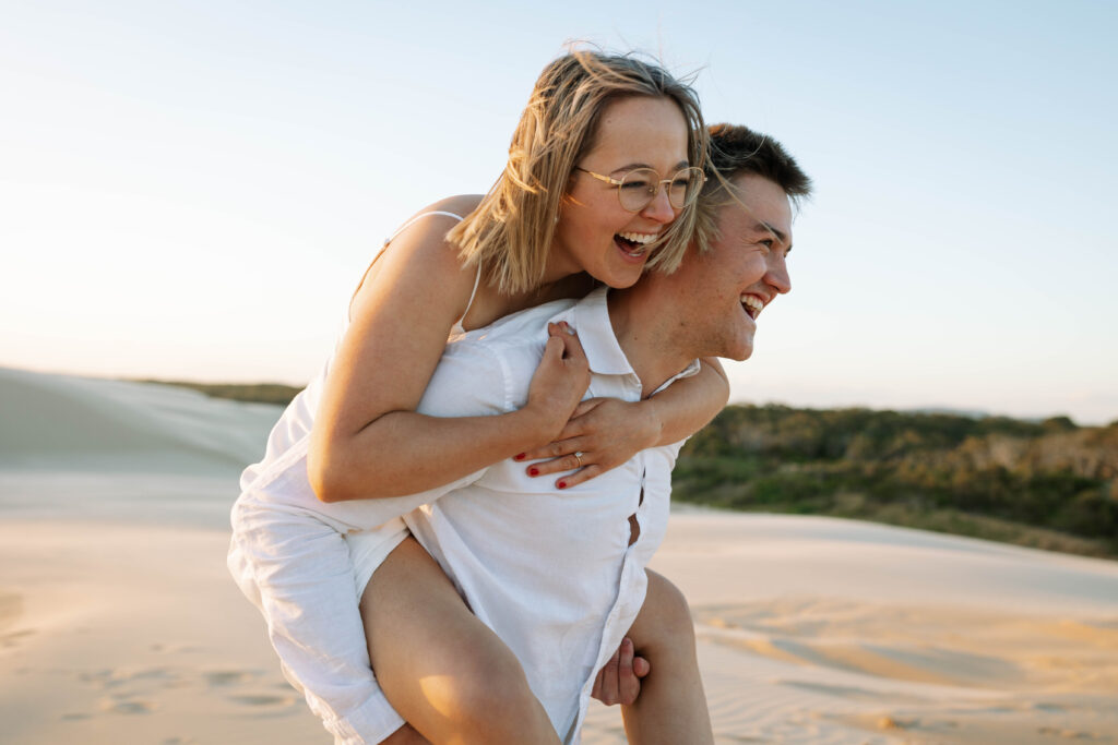 Engagement session sunset at Stockton sand dunes. Piggy back ride