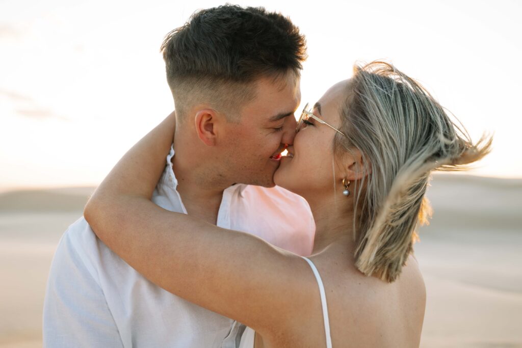Engagement session sunset at Stockton sand dunes with the couple kissing