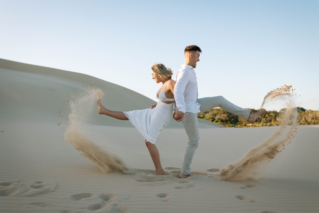 Couple kicking sand on the sand dunes, Port Stephens