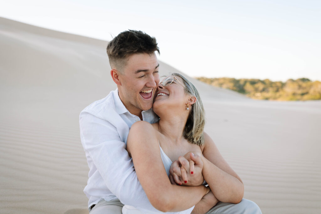 Engagement session sunset at Stockton sand dunes. Couple cuddling