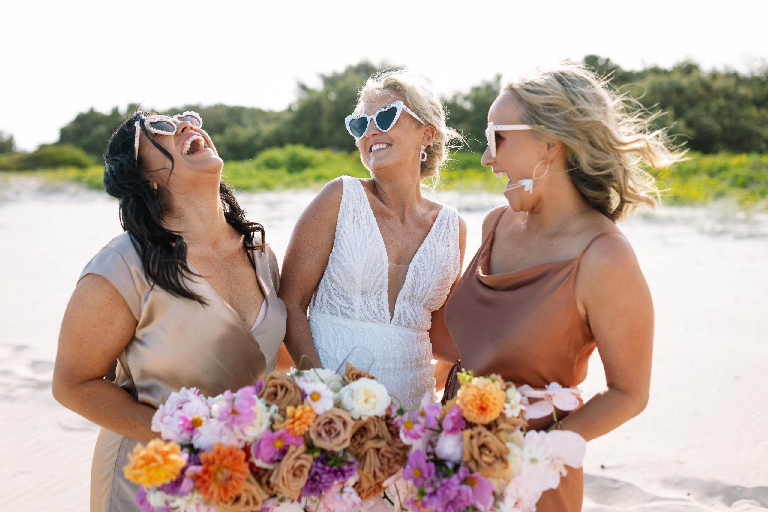 Bridesmaids on the beach with heart sun glasses and their bouquets