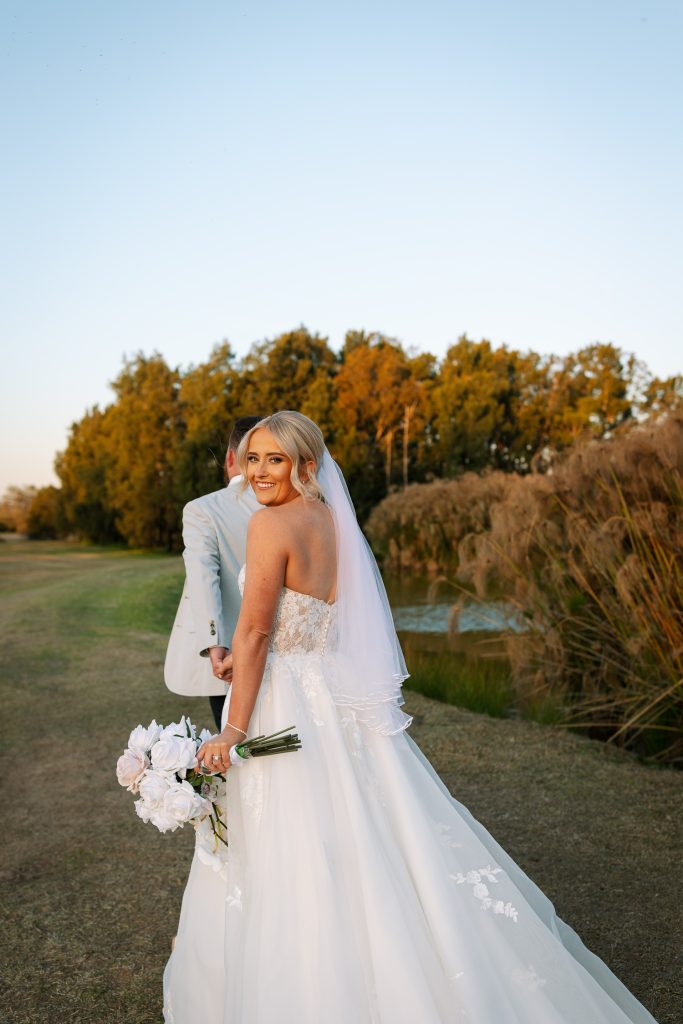 bride looking over her shoulder whilst walking with her husband at a wedding in the hunter valley